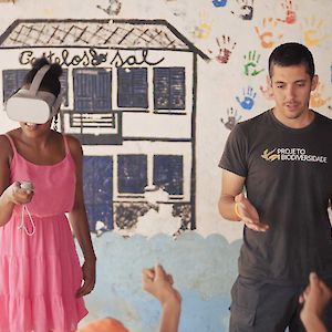 Schoolgirl in Cape Verde wearing an oculus virtual reality headset while tutor speaks